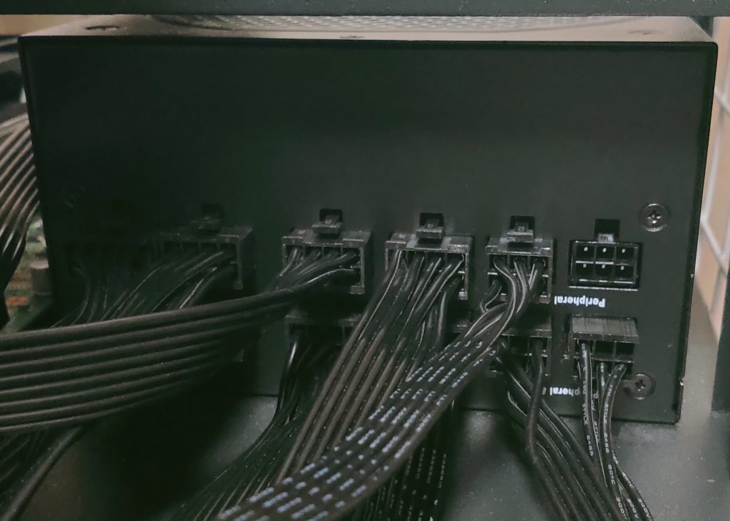 Back of a fully modular ATX power supply with black sleeved cables plugged into its ports