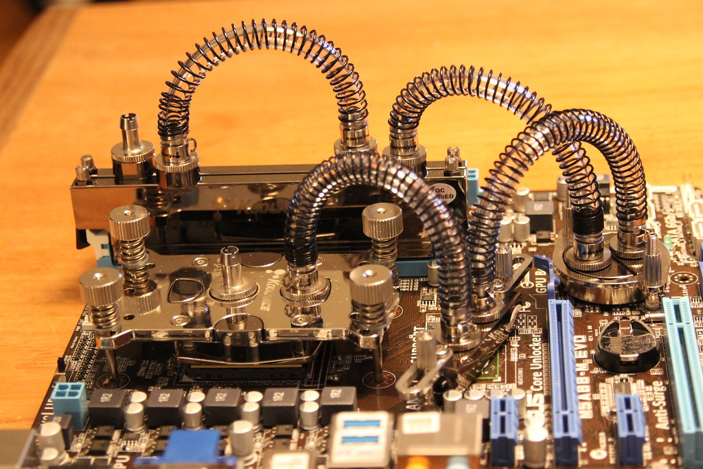 Motherboard fitted with water blocks and spring-wrapped tubing for a custom liquid cooling loop